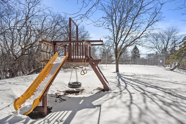 snow covered playground featuring fence and a playground