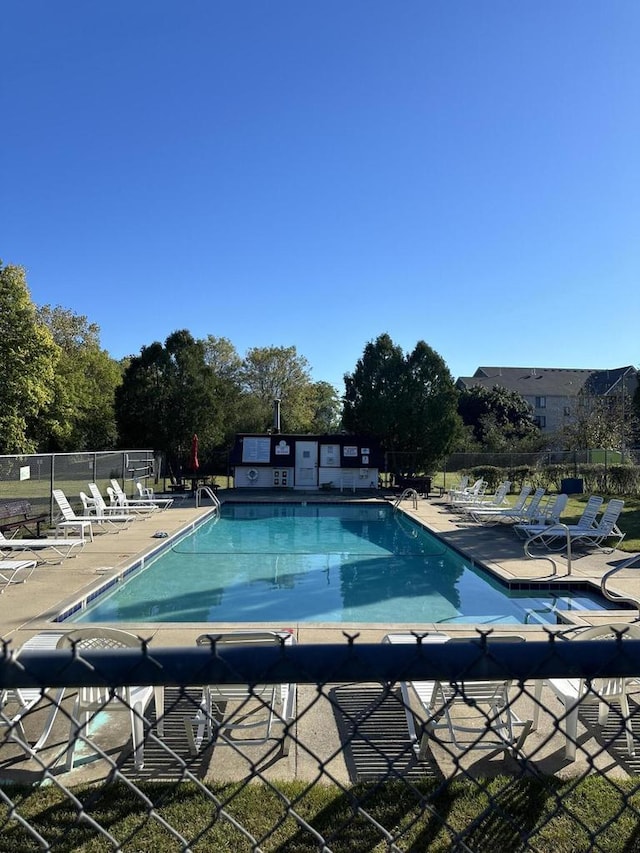 community pool with a patio area and fence