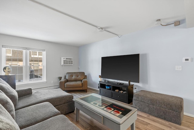 living room with baseboard heating, a wall unit AC, wood finished floors, and baseboards