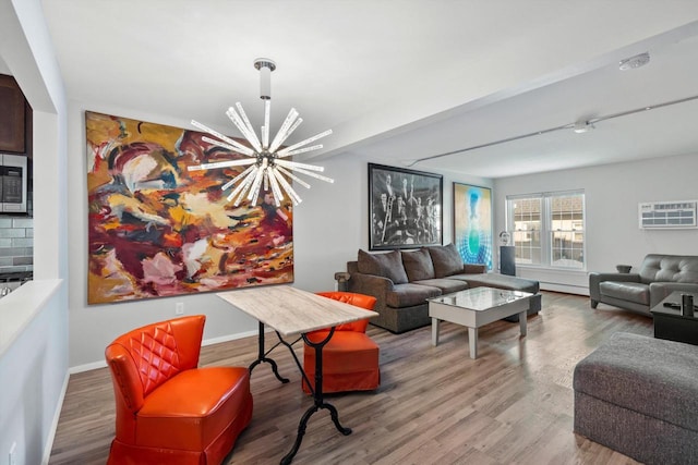 living room with baseboard heating, baseboards, a chandelier, and wood finished floors