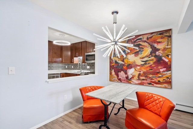 dining area featuring a baseboard heating unit, a notable chandelier, baseboards, and wood finished floors