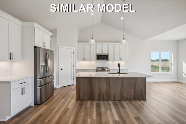 kitchen featuring white cabinets, appliances with stainless steel finishes, wood finished floors, light countertops, and a sink