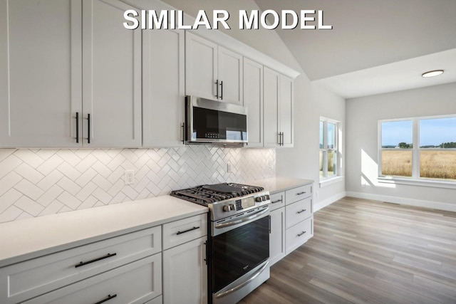 kitchen featuring light countertops, decorative backsplash, appliances with stainless steel finishes, white cabinetry, and wood finished floors