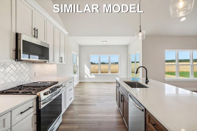 kitchen featuring wood finished floors, a sink, light countertops, appliances with stainless steel finishes, and decorative backsplash