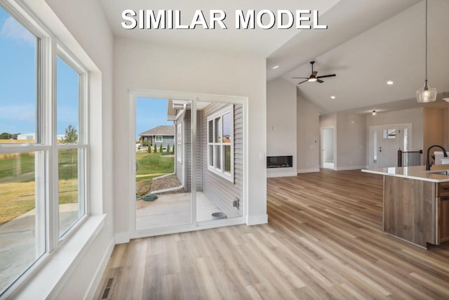 interior space featuring baseboards, lofted ceiling, wood finished floors, a sink, and recessed lighting