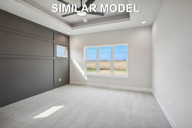 unfurnished room with a ceiling fan, baseboards, a tray ceiling, and carpet flooring