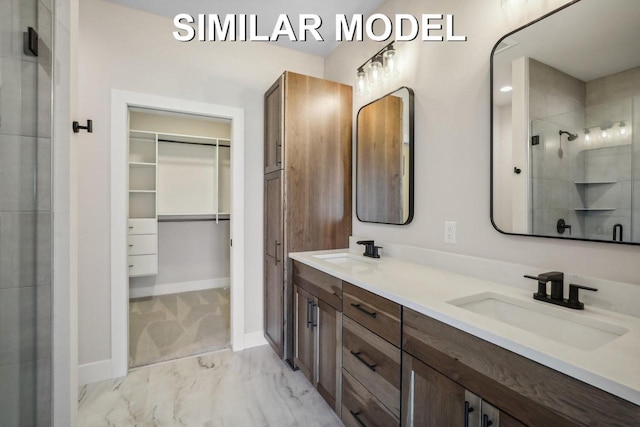 bathroom featuring marble finish floor, a sink, a walk in closet, and a shower stall