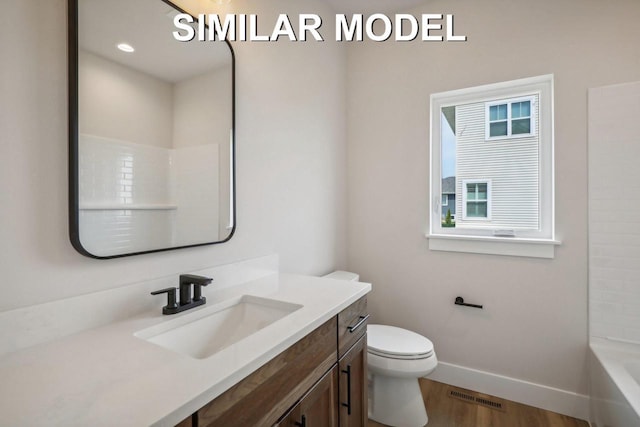 bathroom with toilet, wood finished floors, vanity, visible vents, and baseboards