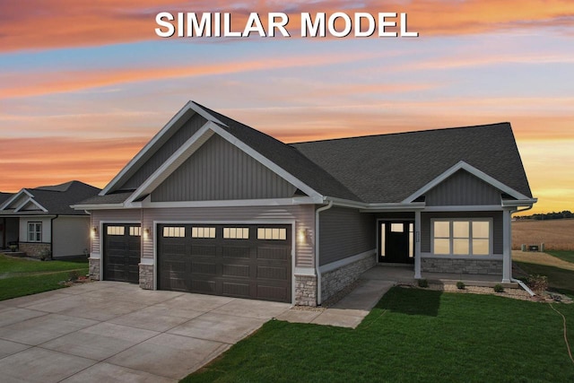 craftsman-style house featuring an attached garage, stone siding, concrete driveway, a lawn, and board and batten siding