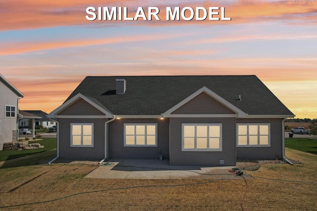 view of front facade featuring a front yard, a patio area, a chimney, and roof with shingles