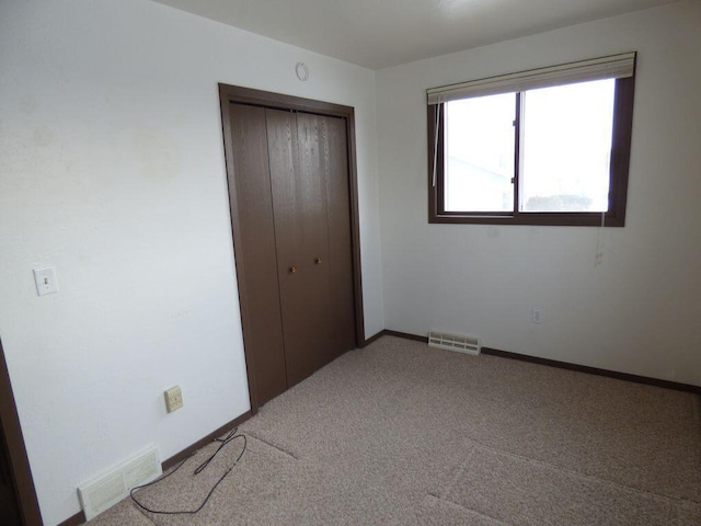 unfurnished bedroom with baseboards, visible vents, a closet, and carpet flooring