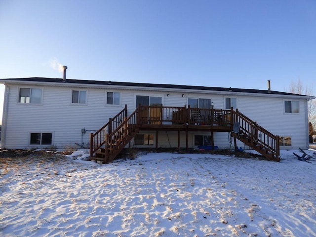 snow covered house featuring stairway and a wooden deck