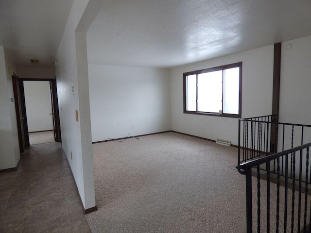 unfurnished room with carpet floors, visible vents, and baseboards