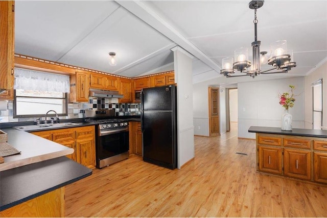 kitchen with stainless steel gas range, brown cabinets, freestanding refrigerator, and under cabinet range hood