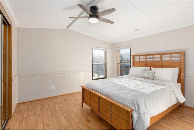 bedroom with vaulted ceiling with beams, ceiling fan, wood finished floors, and wainscoting