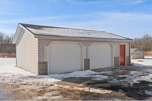 snow covered garage with a detached garage