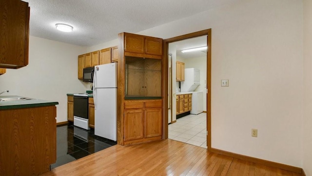 kitchen featuring white appliances, brown cabinetry, wood-type flooring, a textured ceiling, and a sink