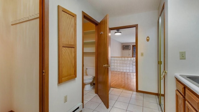 bathroom with a baseboard radiator, toilet, vanity, baseboards, and tile patterned floors