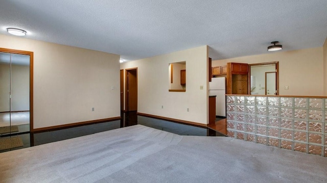 empty room featuring a textured ceiling and baseboards