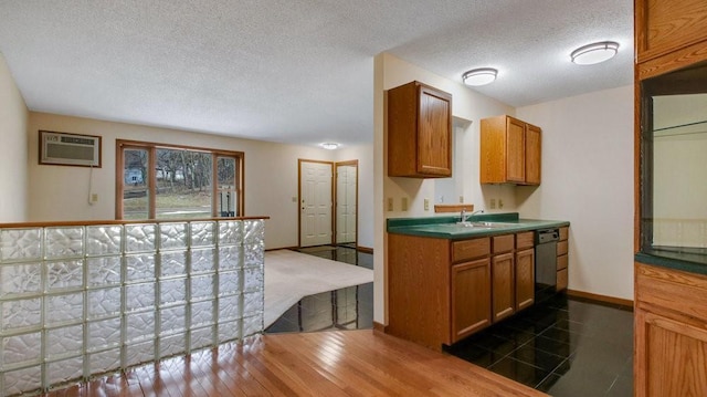 kitchen featuring a textured ceiling, black dishwasher, a wall mounted AC, brown cabinets, and dark wood-style floors