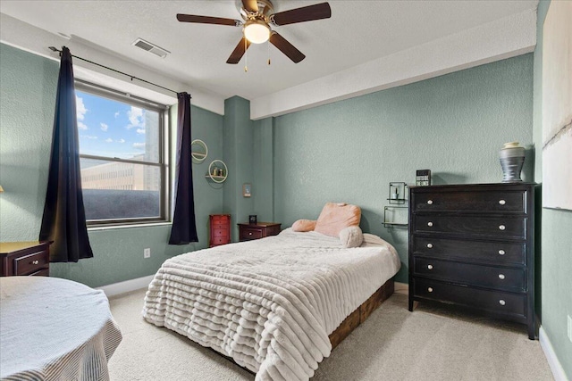 bedroom featuring carpet floors, visible vents, a textured wall, and baseboards