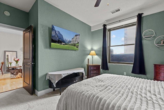 carpeted bedroom featuring baseboards, visible vents, a ceiling fan, and a textured wall