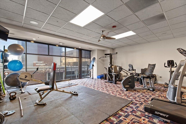 workout area featuring expansive windows, visible vents, a drop ceiling, and baseboards