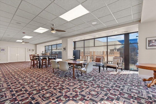 dining space with a paneled ceiling, ceiling fan, baseboards, and carpet flooring