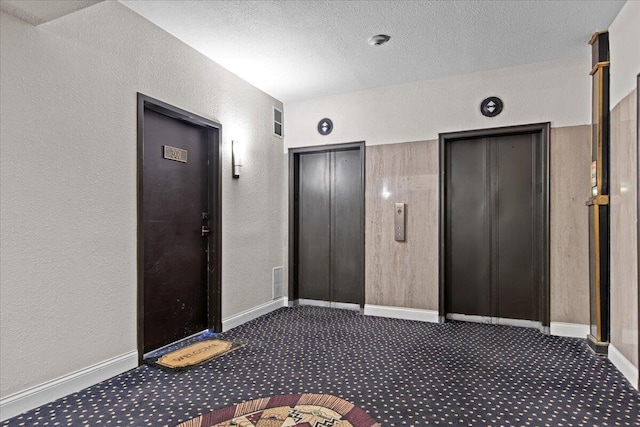 interior space with elevator, carpet, and a textured wall