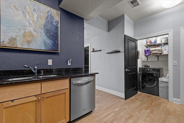 kitchen featuring light wood-style flooring, a sink, visible vents, dishwasher, and washer / clothes dryer