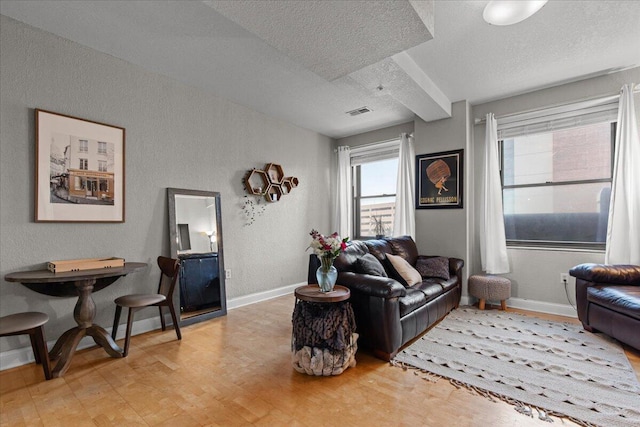 living room with baseboards, visible vents, light wood finished floors, and a textured ceiling