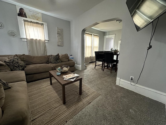 carpeted living room featuring arched walkways and baseboards