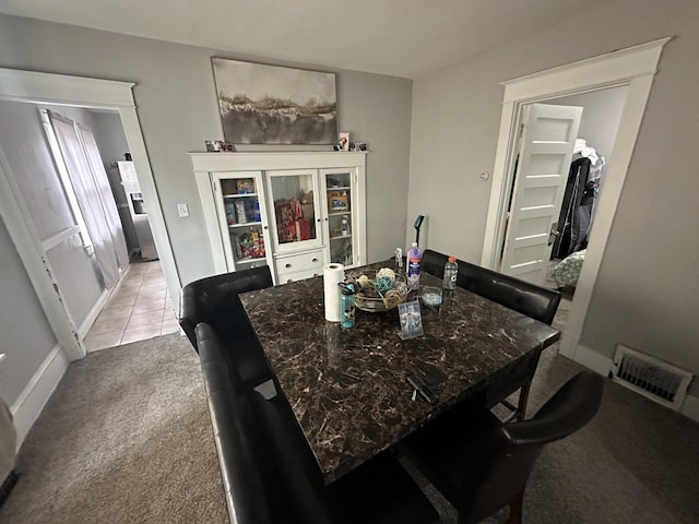 dining space featuring light carpet, light tile patterned floors, baseboards, and visible vents