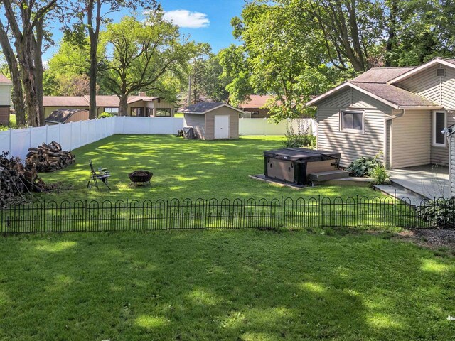 605 S Adams Ave, Marshfield, WI 54449 - view of yard featuring an outdoor fire pit, a fenced backyard, a storage shed, an outdoor structure, and a hot tub