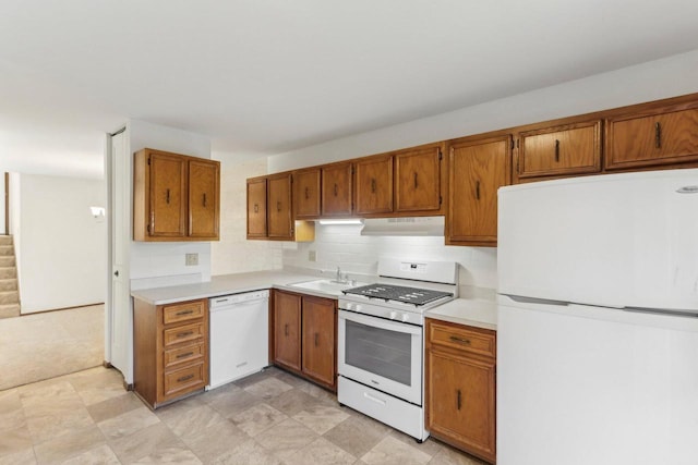 kitchen featuring white appliances, under cabinet range hood, light countertops, and a sink