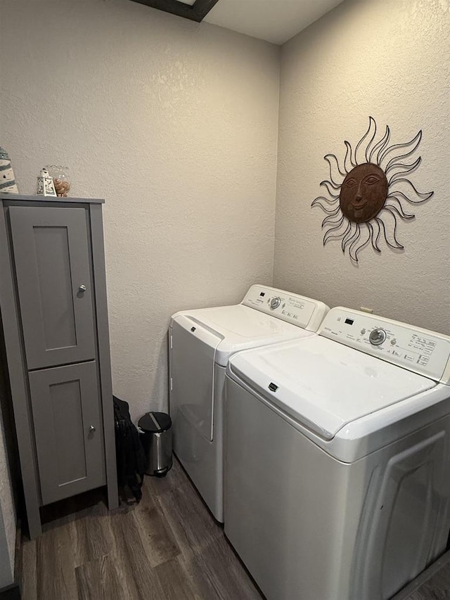 laundry room featuring laundry area, a textured wall, dark wood-type flooring, and washing machine and clothes dryer