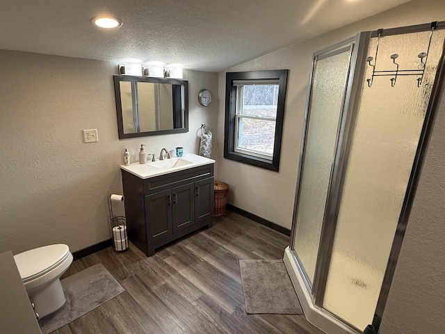 full bath featuring wood finished floors, a textured ceiling, a shower stall, vanity, and baseboards