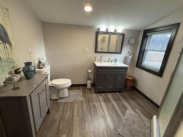 bathroom featuring a textured ceiling, toilet, wood finished floors, vanity, and baseboards