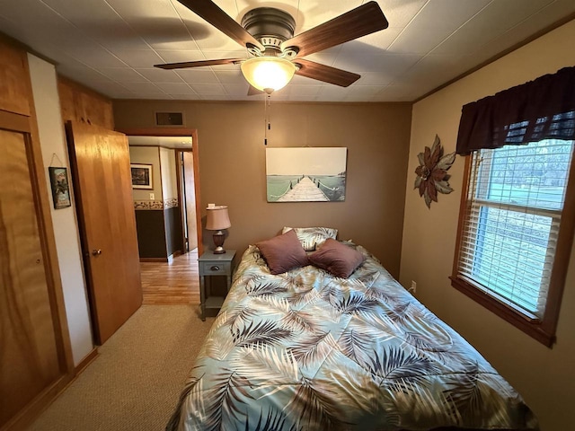 bedroom with a ceiling fan, light colored carpet, and visible vents