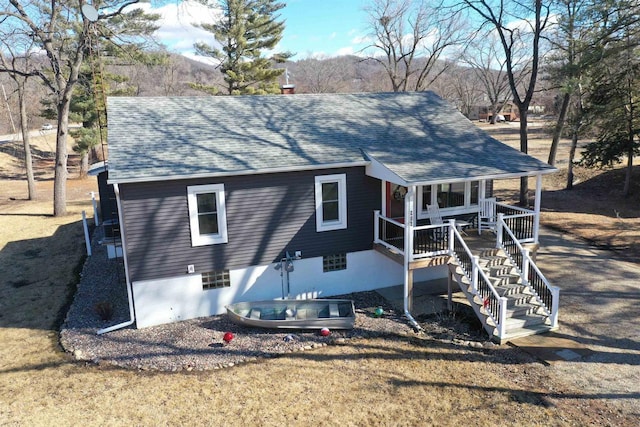 back of property with a porch, roof with shingles, a chimney, and stairs