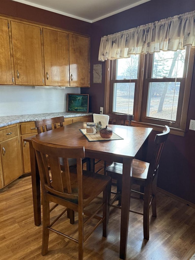 dining area featuring crown molding, light wood-type flooring, and baseboards