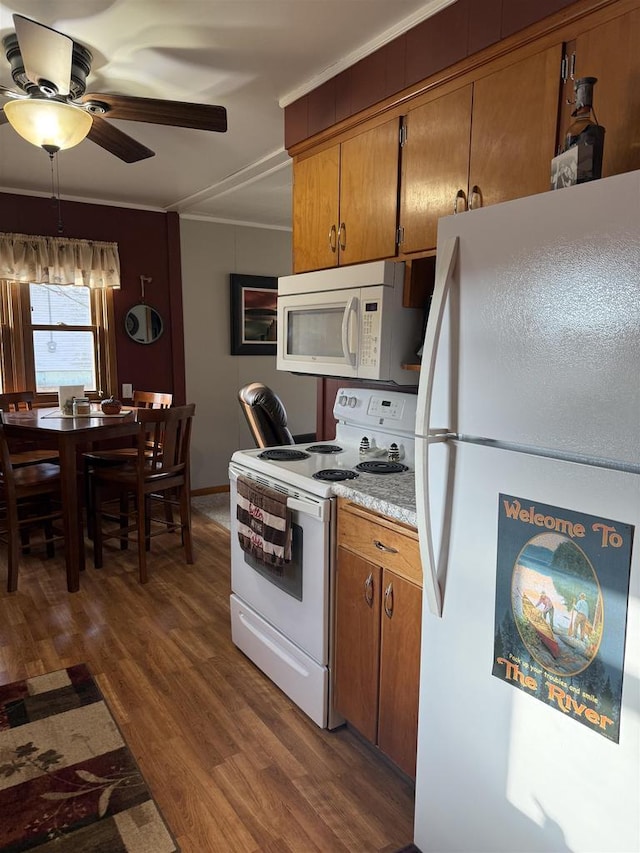 kitchen featuring dark wood-style flooring, brown cabinets, light countertops, a ceiling fan, and white appliances