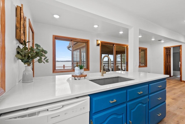 kitchen featuring white dishwasher, light wood-style flooring, recessed lighting, blue cabinets, and a sink