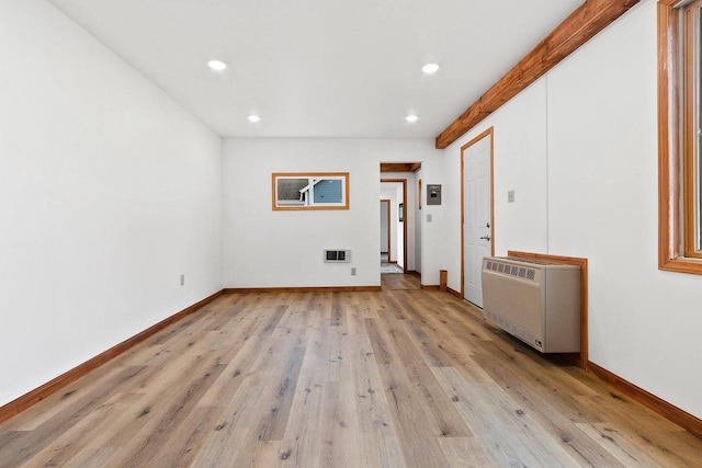 empty room featuring light wood-type flooring, radiator, baseboards, and recessed lighting