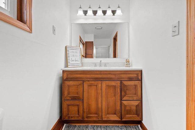 bathroom featuring visible vents, vanity, baseboards, and walk in shower