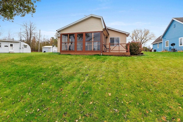 rear view of property featuring a deck, a lawn, and a sunroom