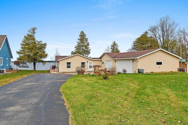 ranch-style home featuring a garage, aphalt driveway, cooling unit, and a front yard