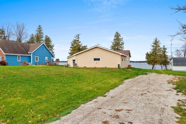 view of home's exterior featuring gravel driveway, a water view, and a yard