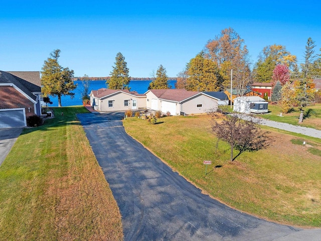 view of front of property featuring driveway, a front lawn, a water view, and a residential view