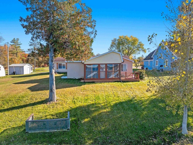 exterior space featuring an outbuilding, a storage unit, a lawn, and a sunroom